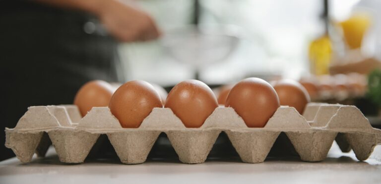 Eggs in carton container placed on table near chef cooking food in kitchen